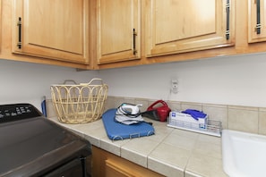 A kitchen with wooden cabinets, a basket, an iron, and a dish rack. - Luxury home in the heart of Roseville, CA. Resort-Style salt water pool and more (Roseville)