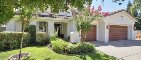 A residential house with a garage, a well-maintained lawn, and a variety of plants.