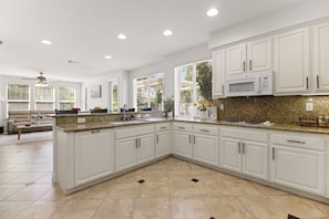 A spacious kitchen with white cabinetry, granite countertops, and a large island. - Luxury home in the heart of Roseville, CA. Resort-Style salt water pool and more (Roseville)