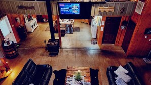 A spacious room with a large television, leather sofas, a wooden coffee table, and a rustic decor. - 4-bedroom Open concept Farmhouse minutes from Norfork Lake (Clarkridge)