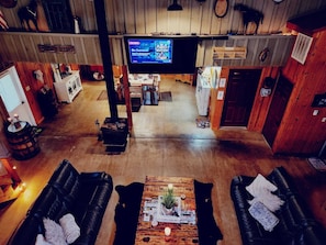 A spacious room with a large television, leather sofas, a wooden coffee table, and a rustic decor.