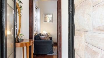 A hallway leading to a bedroom with a bed, a bedside table, and a wall-mounted picture.