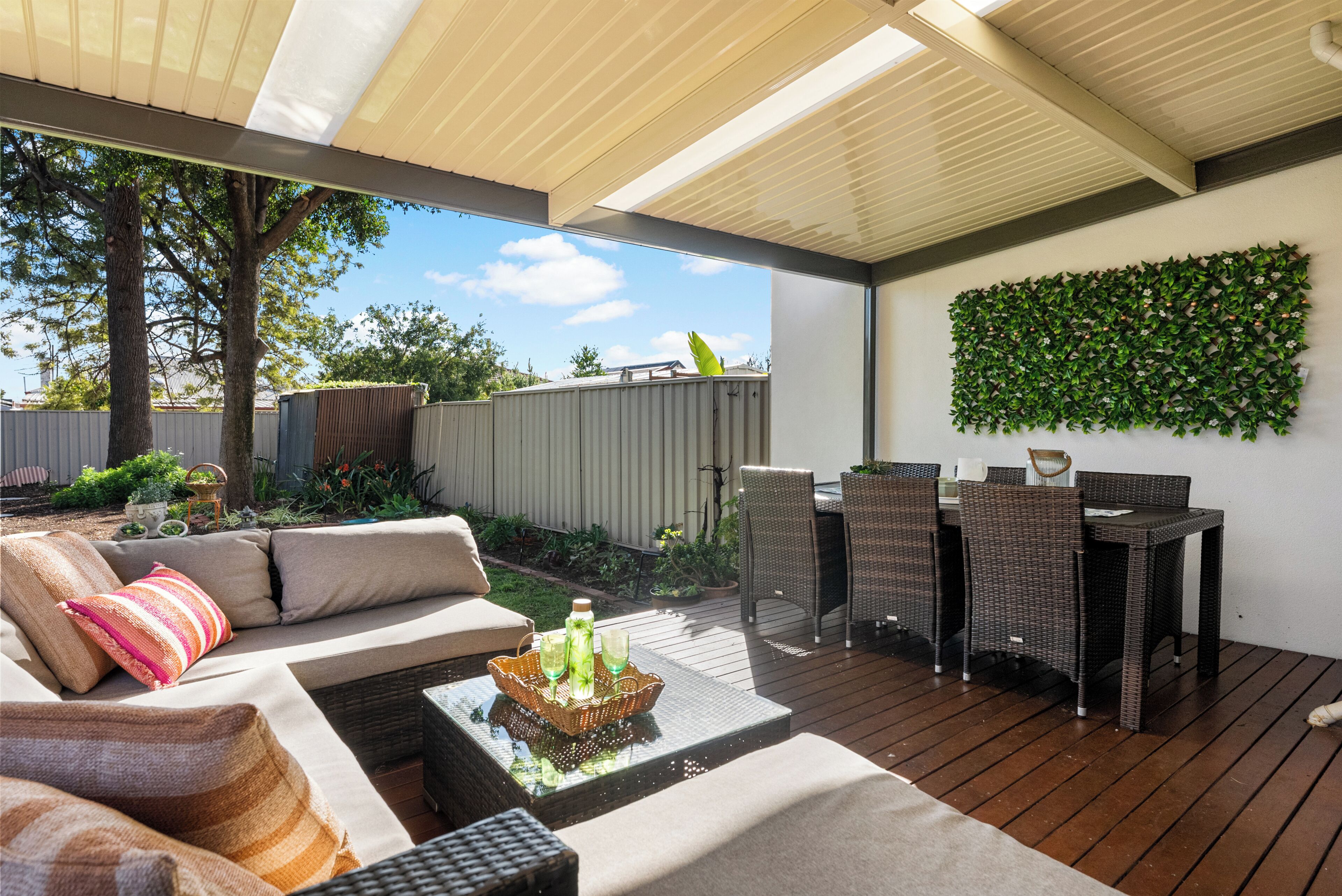 An outdoor patio with a sofa, dining table, and chairs.