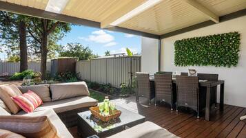 An outdoor patio with a sofa, dining table, and chairs.