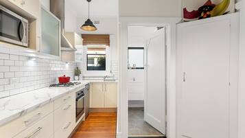 A modern kitchen with white cabinetry, a stove, and a microwave.