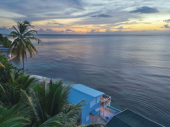 A coastal view with a building featuring a balcony overlooking the sea.
