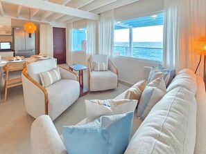 A modern living room with a sofa, armchairs, and a dining area.