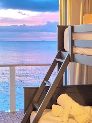 A room with a bed, a ladder, and a view of the sea.