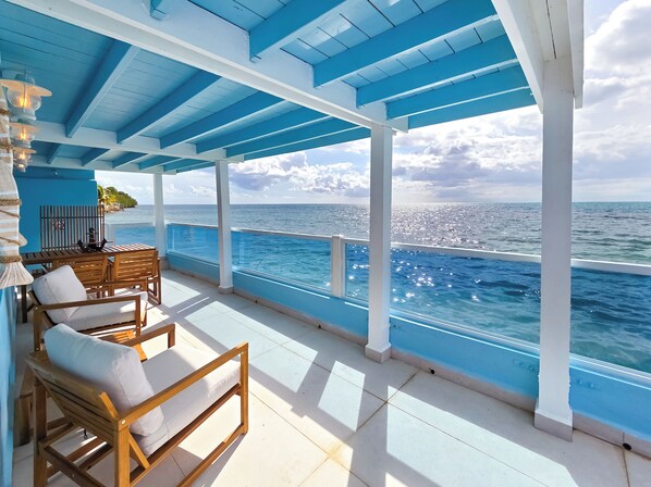 A covered outdoor seating area with a view of the ocean.