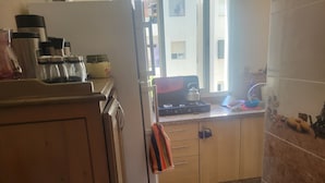 Een keuken met een gasfornuis, kastjes en een raam.