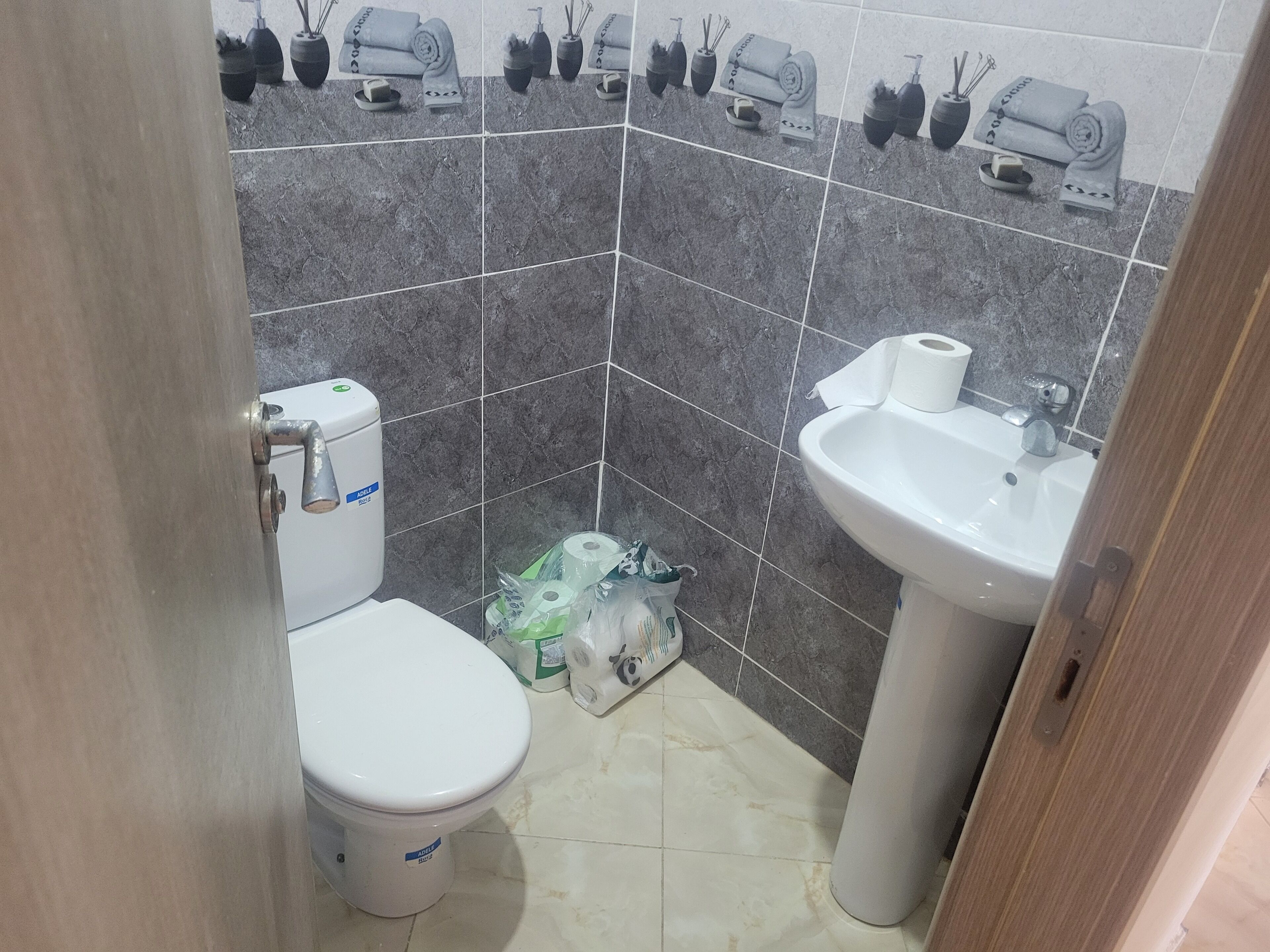 A bathroom with a toilet, sink, and tiled walls.
