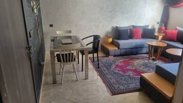 A living area with a sofa, a coffee table, a rug, and a dining table with chairs.