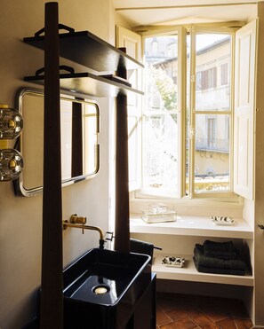 A bathroom with a large mirror, a sink, and a window with a view of buildings. - Borgo Santa Croce Design Florence Luxury Management (Firenze)