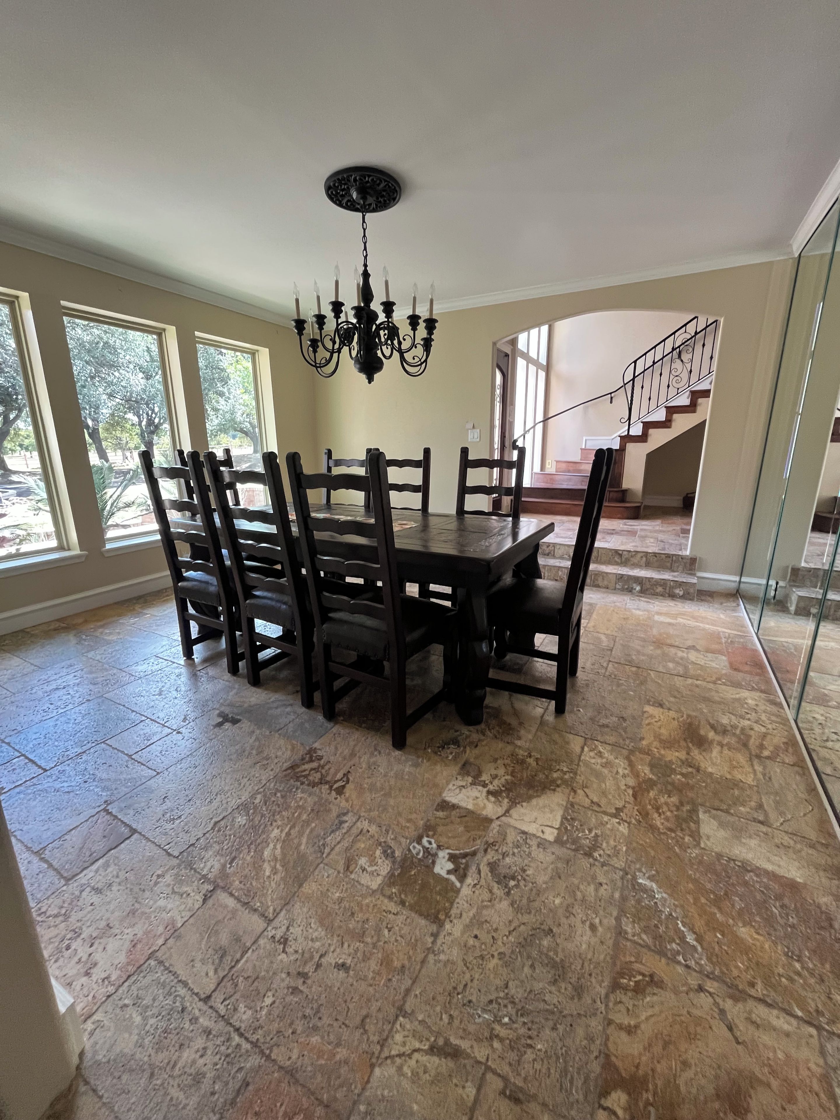A dining area with a chandelier, large windows, and a staircase leading to an upper level.