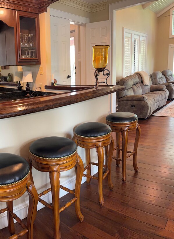 A bar area with wooden stools and a glass-top bar counter.