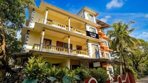 A multi-story hotel with a yellow facade, balconies with golden railings, and a sign indicating it is a company-serviced hotel. - Saver Double Crystal Holiday Homes (Calangute)