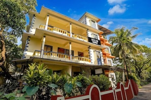 A multi-story hotel with a yellow facade, balconies with golden railings, and a sign indicating it is a company-serviced hotel. - Saver Double Crystal Holiday Homes (Calangute)