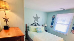 A bedroom with a bed, a nightstand, a lamp, and a star decoration on the wall.