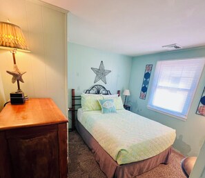 Une chambre à coucher avec un lit, une table de chevet, une lampe et une décoration en forme d’étoile sur le mur.