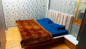 A room with a bed, a mirror, and floral wallpaper. - Hotel Nityam Stay (Ujjain)