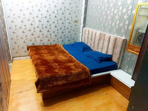 Una habitación con una cama, un espejo y papel tapiz con motivos florales.