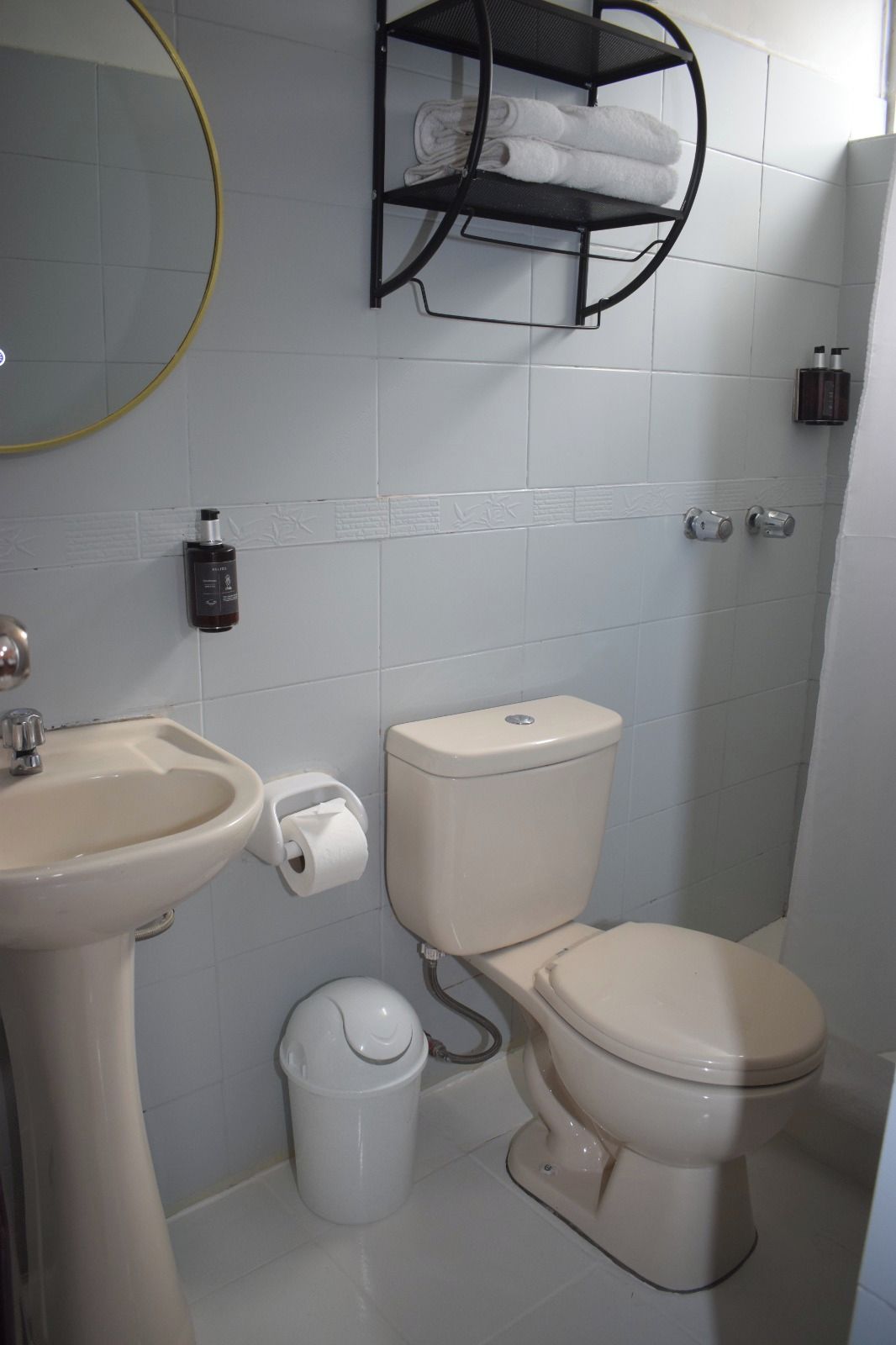 Un baño con lavamanos, inodoro y un perchero para toallas.