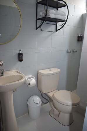 Un baño con lavamanos, inodoro y un perchero para toallas.