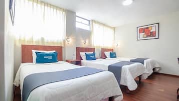 A hotel room with three beds, each with a blue headboard and a pillow labeled 'ayenda hotel'.