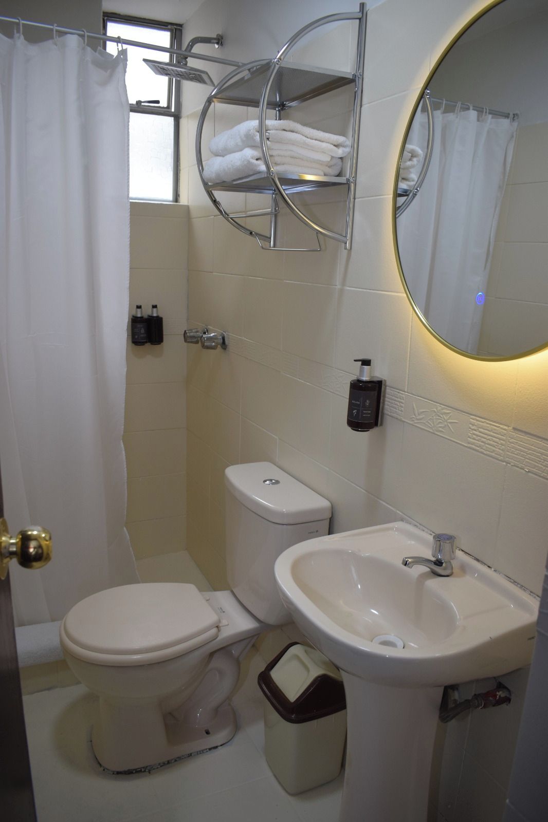 Un baño con inodoro, bidé, lavamanos y un perchero para toallas.