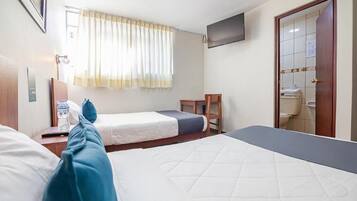 Habitación de hotel con dos camas, un televisor, una ventana con cortinas y una puerta que da a un baño.