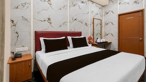 Ein Hotelzimmer mit Bett, Nachttisch, Spiegel und Tür.