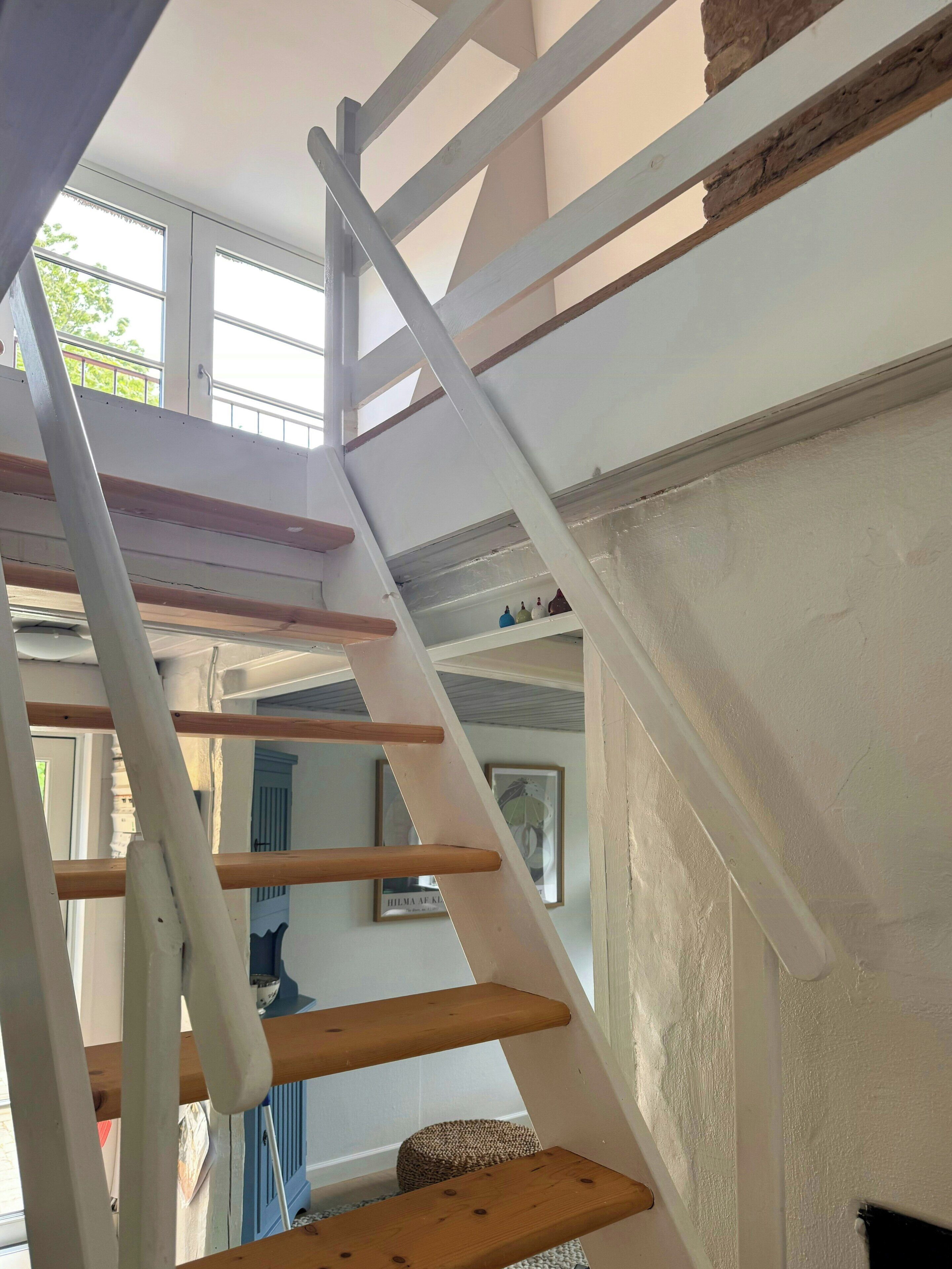 A white interior staircase with wooden steps and a white handrail.