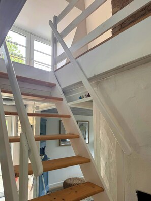 Un escalier intérieur blanc, avec des marches en bois et une rampe blanche.