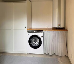 A compact laundry room with a washing machine, a dryer, and a wooden countertop. - Historic house from 1827 on Langeland (Rudkøbing)