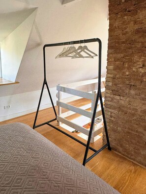 Habitació amb llit, penjador i sòl de fusta.