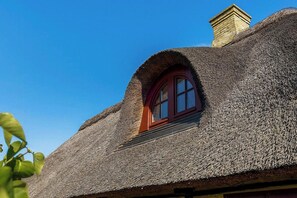 A thatched-roof building with a small arched window and a chimney. - Historic house from 1827 on Langeland (Rudkøbing)