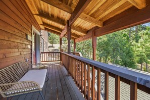 A wooden deck with a table and chairs, overlooking a forested area. - Sunlit Mountain Retreat Near Lakes & Ski Fun (Arnold)