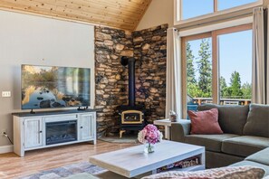Ein Wohnzimmer mit Kamin aus Stein, einem Fernseher und einer Couch.