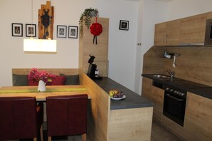 Eine moderne Küche mit Holzschränken, einem eingebauten Backofen und einem Essbereich mit Tisch und Stühlen.