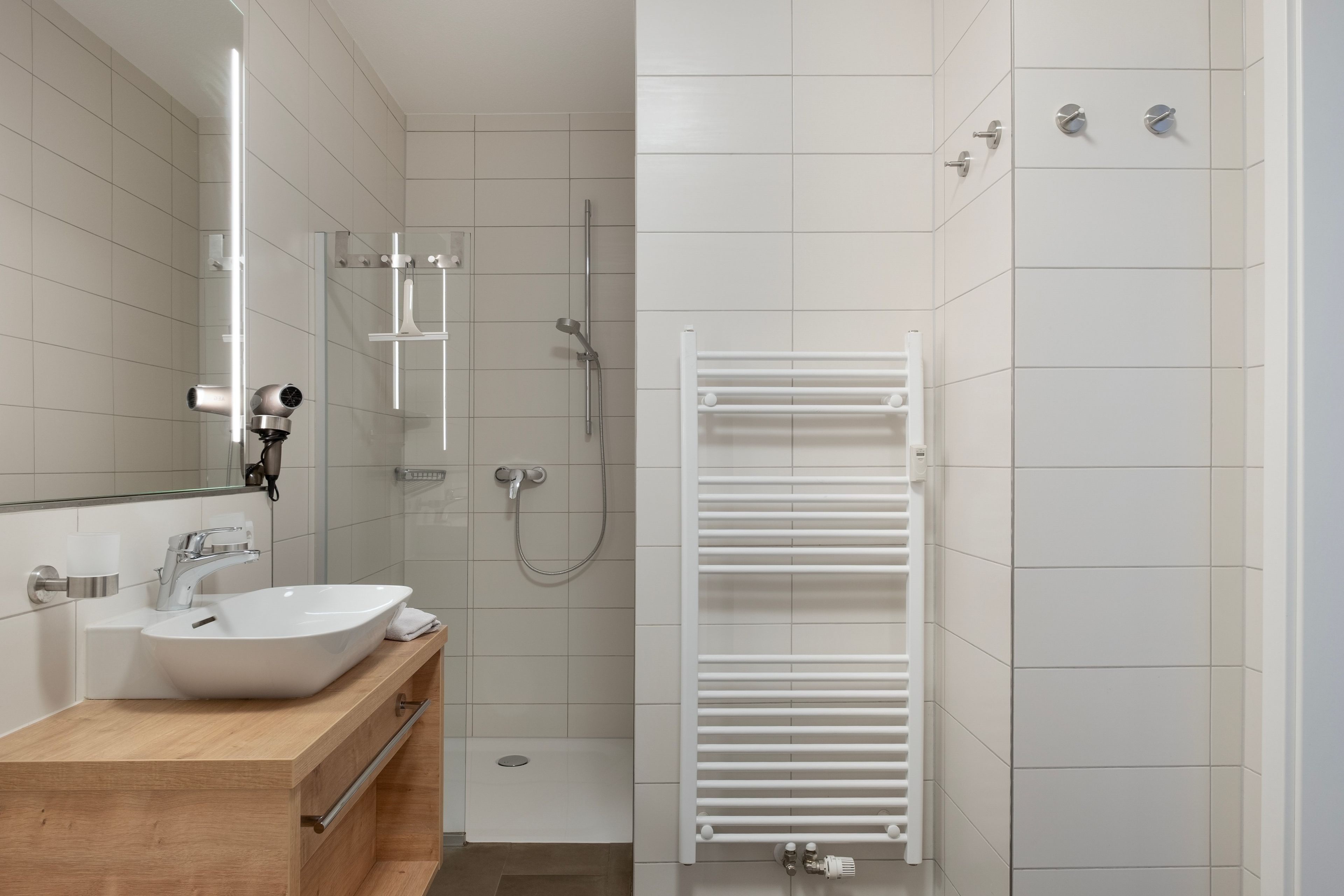 Une salle de bain moderne avec un lavabo blanc, un miroir et une douche.