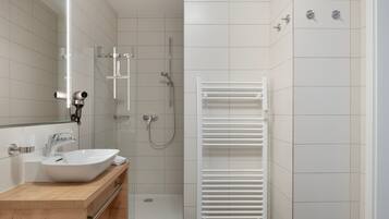 A modern bathroom with a white sink, mirror, and shower.