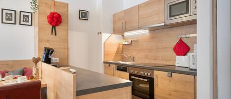 A modern kitchen with wooden cabinetry, a built-in oven, and a microwave.