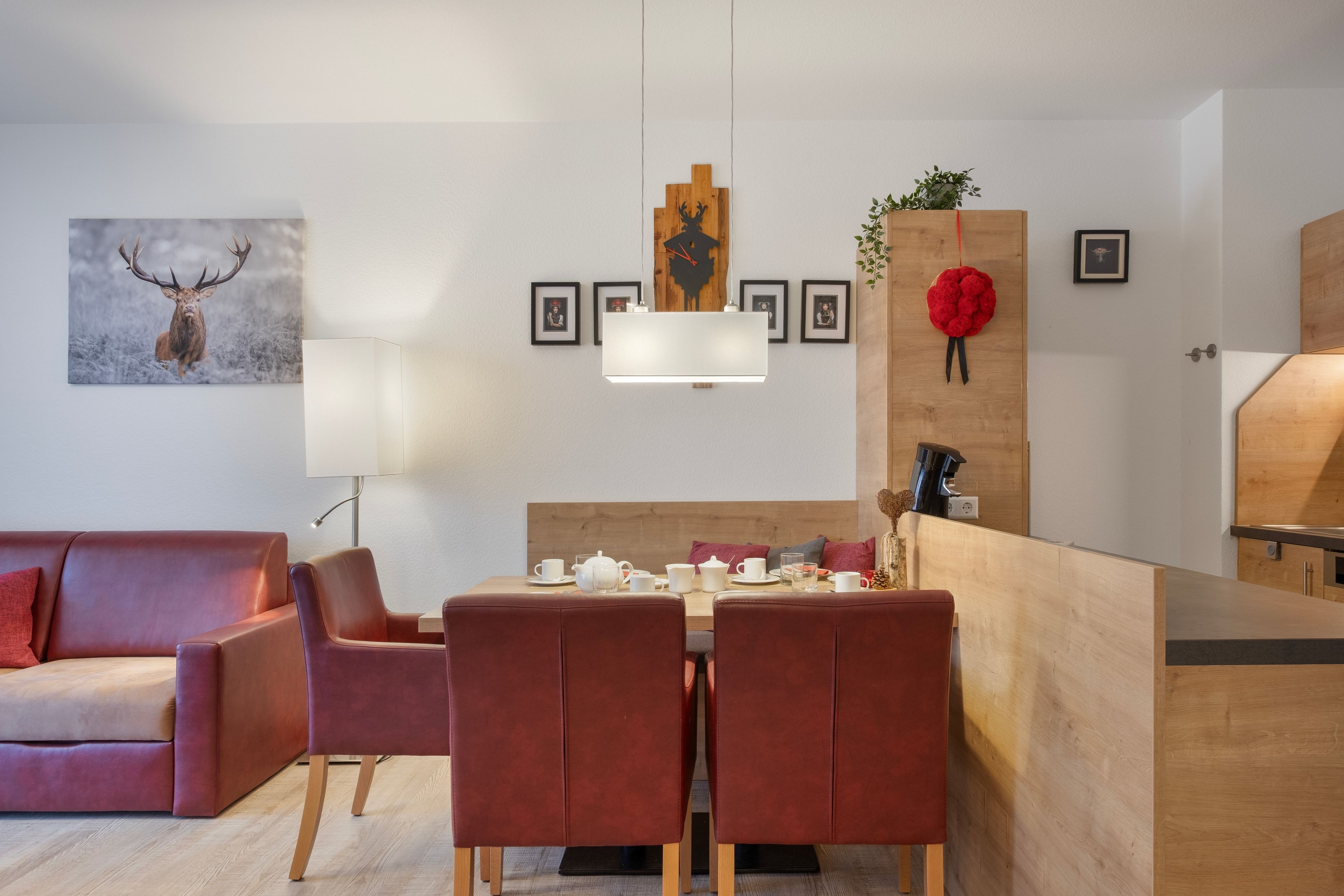 Een moderne woonkamer met een bank, een eettafel gedekt voor twee personen, en een keuken met een houten aanrecht.