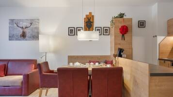Een moderne woonkamer met een bank, een eettafel gedekt voor twee personen, en een keuken met een houten aanrecht.