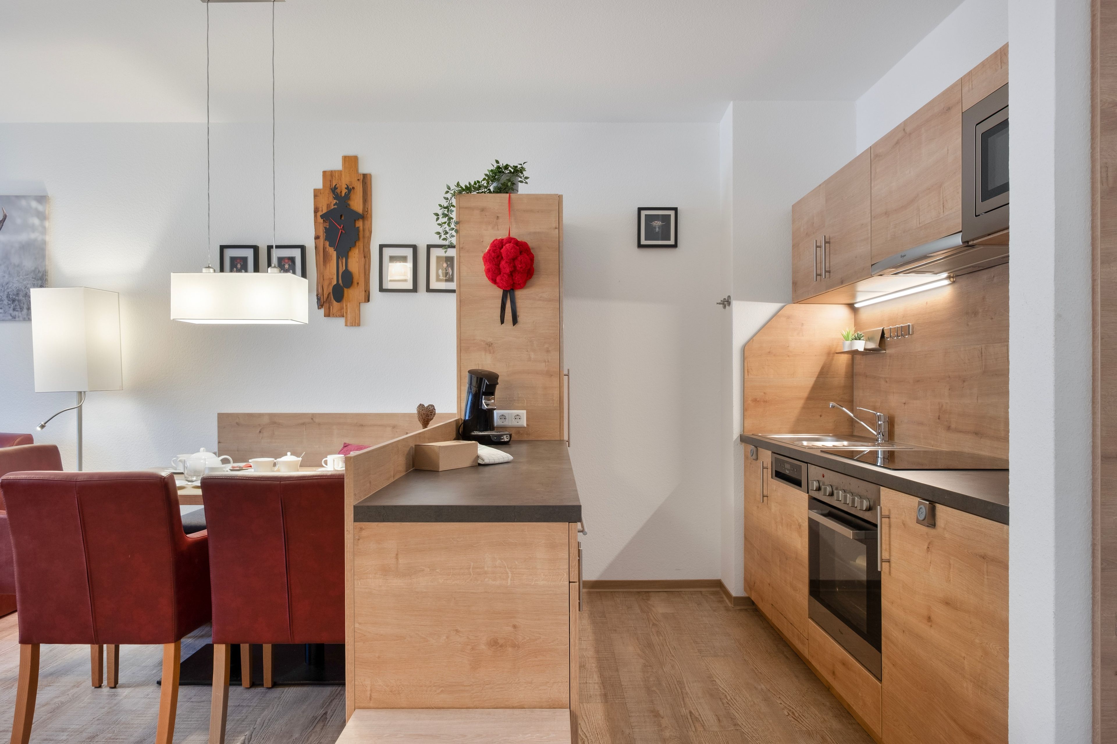 A modern kitchen with wooden cabinetry, a built-in oven, and a coffee machine.