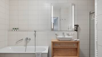 Un baño moderno con una bañera independiente, un tocador de madera con lavabo y un espejo sobre el tocador.