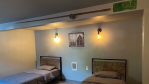 Une chambre avec deux lits, chacun doté d’une tête de lit en bois, d’un petit tableau accroché au mur et de deux lampes fixées au mur.