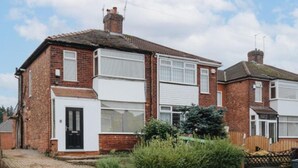 A two-story brick house with a front door, windows, and a garage. - 3 Bedroom House - Pool Table, Opp Train Station (Manchester)