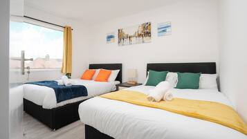 Een hotelkamer met twee bedden, een raam met gordijnen en kunst aan de muur.