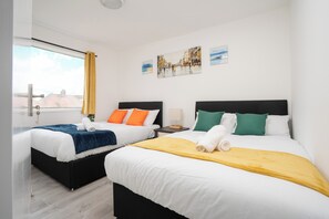 Ein Hotelzimmer mit zwei Betten, einem Fenster mit Vorhängen und einem Bild an der Wand.